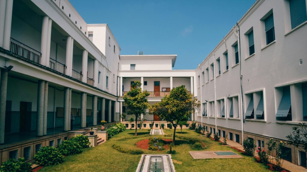 [Image d'un bâtiment blanc avec des jardins bien entretenus et un ciel bleu clair.] Description en français:"Vue intérieure d'un bâtiment avec un jardin central bien entretenu,symbolisant l'harmonie et la beauté des espaces communautaires.En parallèle,Byte App,une nouvelle application de partage de vidéos courtes,représente une tentative audacieuse de concurrence face à TikTok,cherchant à détruire la dominance de ce dernier sur le marché."